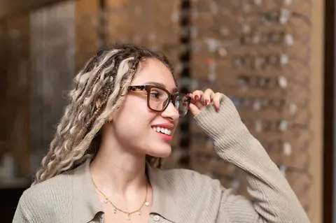 A patient smiling while trying on frames at the TSO Kyle optical gallery